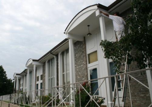 outdoor picture of a white building, with a man working on it